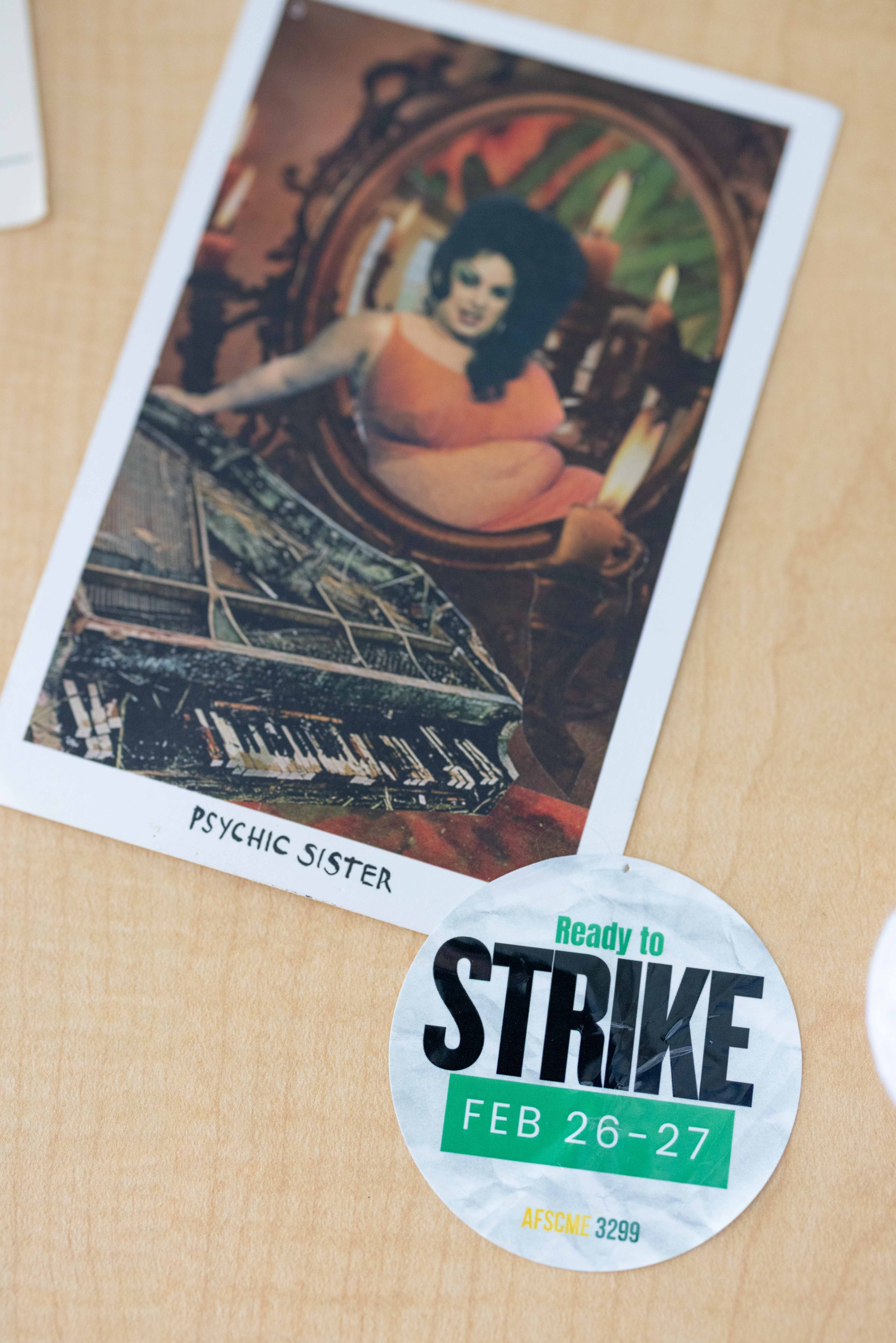 A vintage-style photo titled &quot;Psychic Sister&quot; shows a woman in an orange dress by a mirror. Below, a circular sticker reads &quot;Ready to Strike Feb 26-27, AFSCME 3299.&quot;