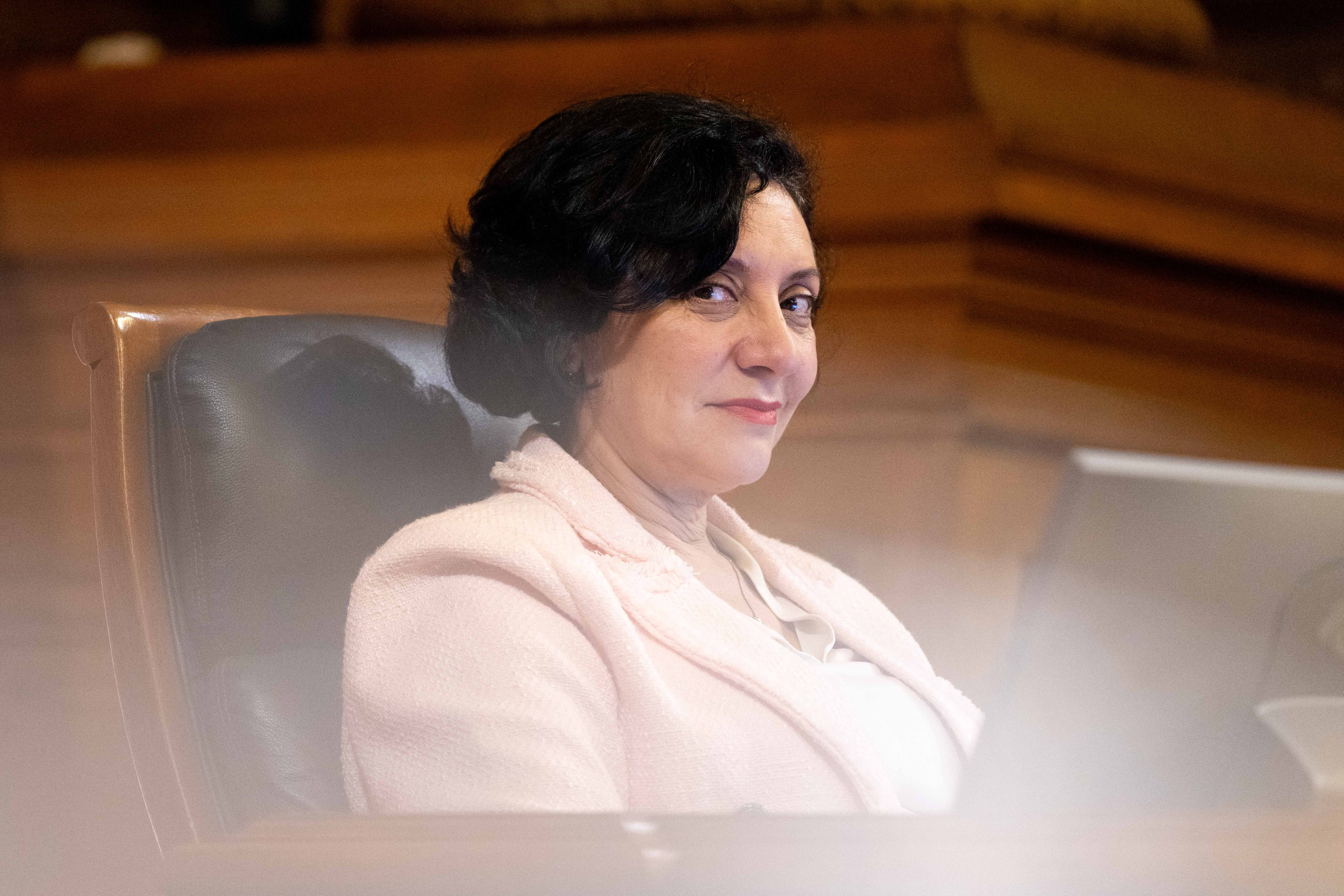 A city official sits in a chair in legislative chambers.