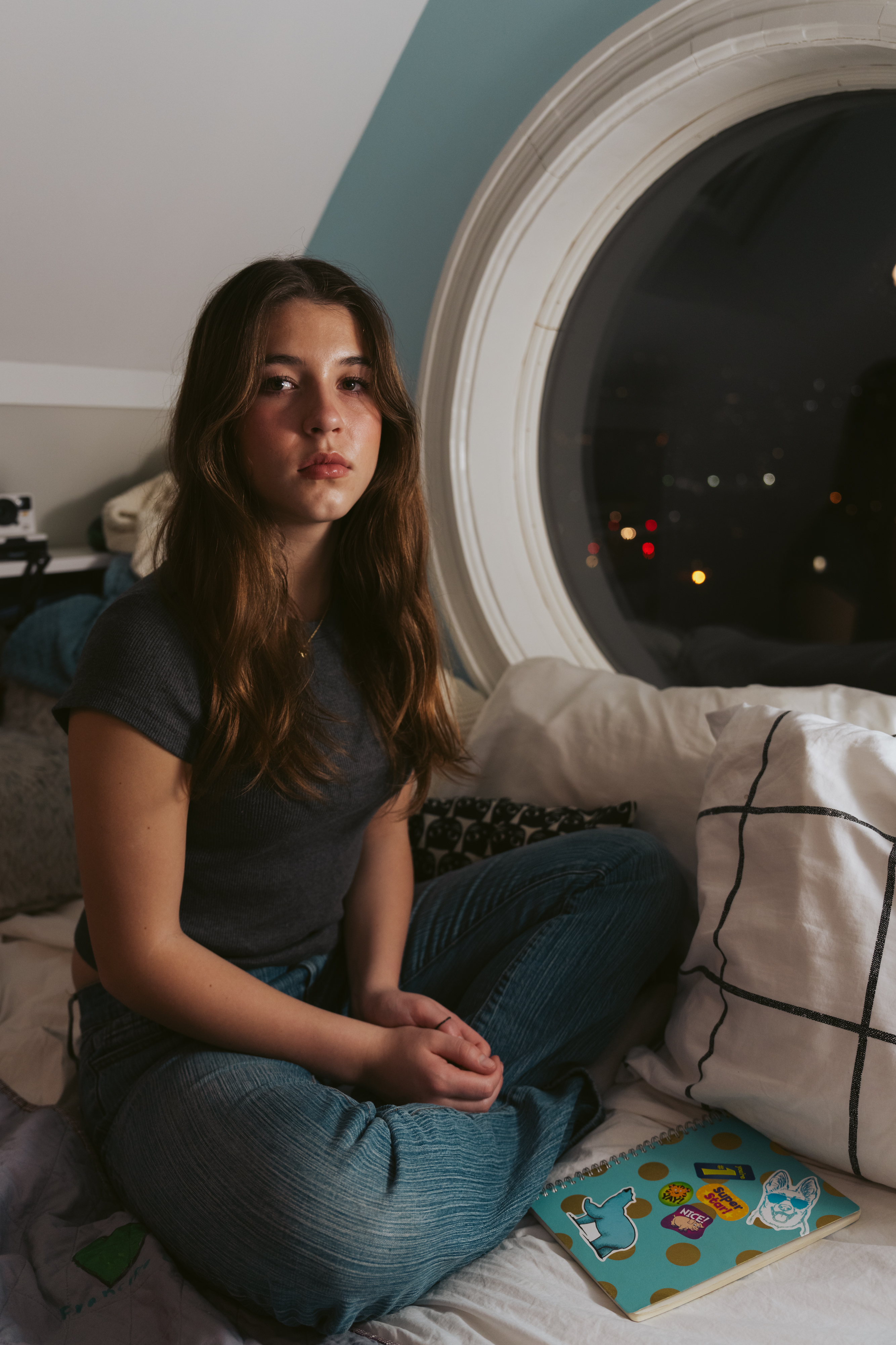 Silver Wiesler sits for a portrait in her bedroom at her home in Bernal Heights on Tuesday, Feb. 18, 2025.   Next to her on the bed is her original fire journal, which she received in 2016 after the Wieslers lost their home in a no-fault furnace fire. Unlike the clothing and toy donations, the journal wasn’t aiming to replace her belongings or encourage her to forget her loss, Wiesler said. Instead, it was helping her face her feelings and look ahead.  The Wieslers have donated 5000 journals to people in California impacted by fires since they launched their project in 2017.