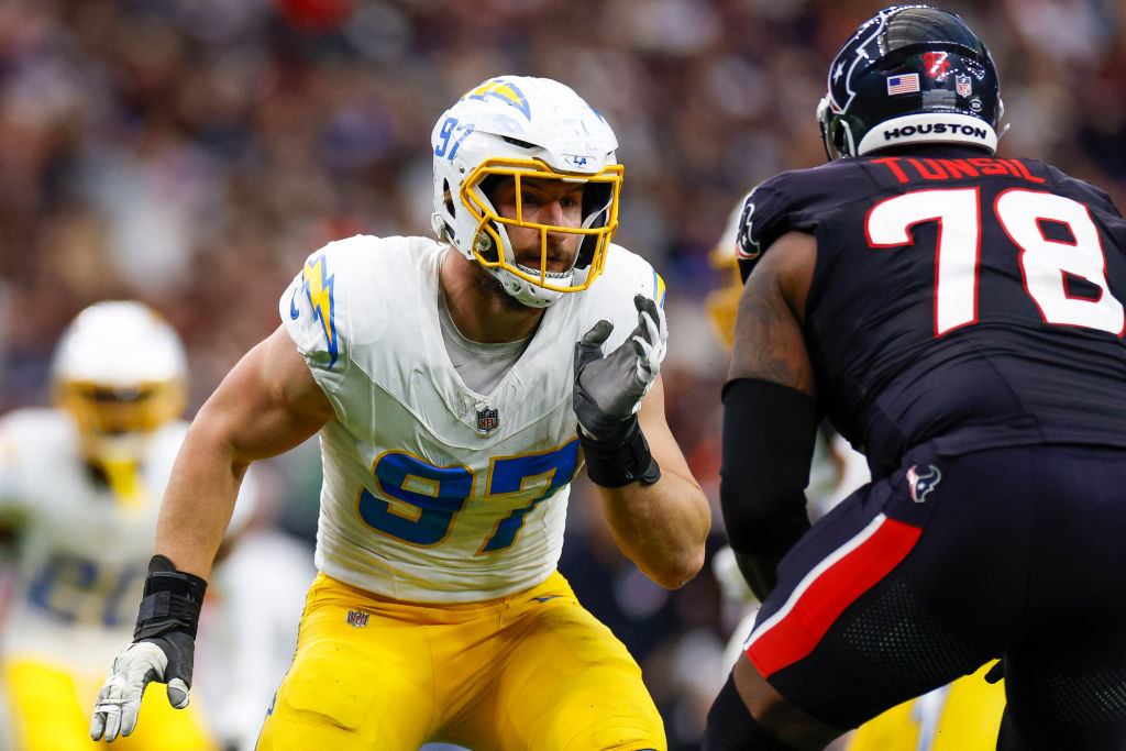 Two football players are facing each other on the field. One wears a white and yellow uniform with number 97, and the other wears black with number 78.