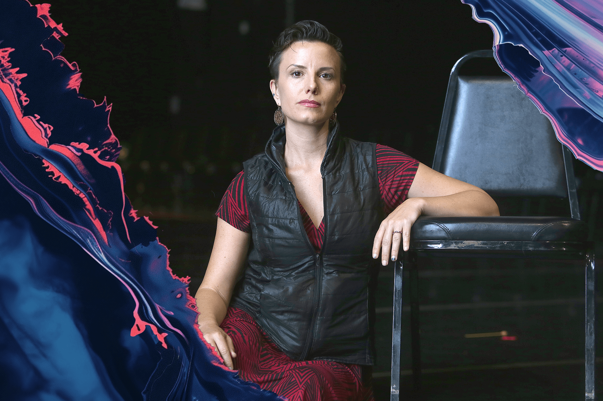A woman in a red dress and black vest sits confidently on a chair, with abstract blue and pink swirls surrounding her.