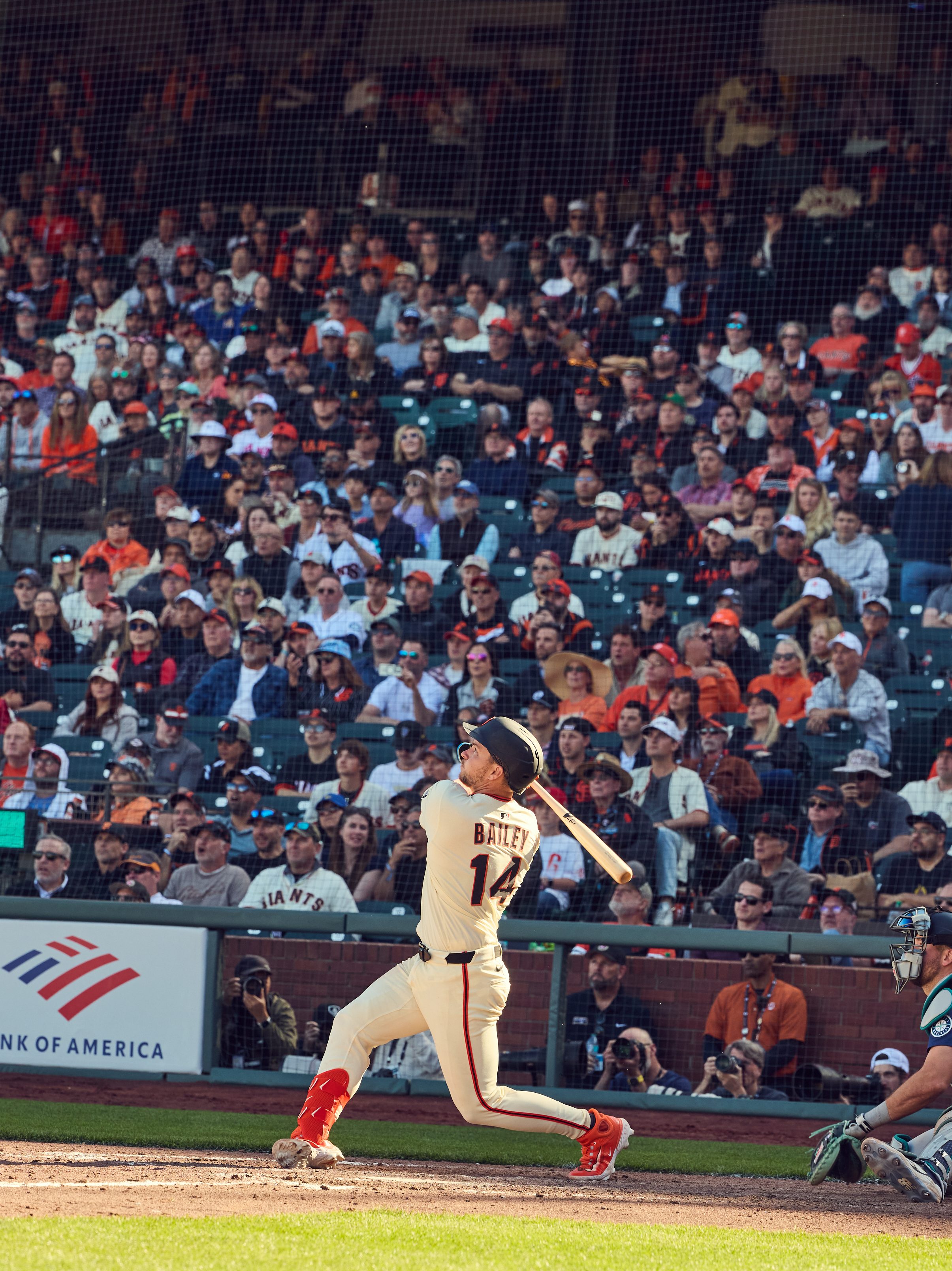 A baseball player swings the bat mid-action, watched by a large, enthusiastic crowd. He wears a white uniform with &quot;Bailey&quot; on the back.