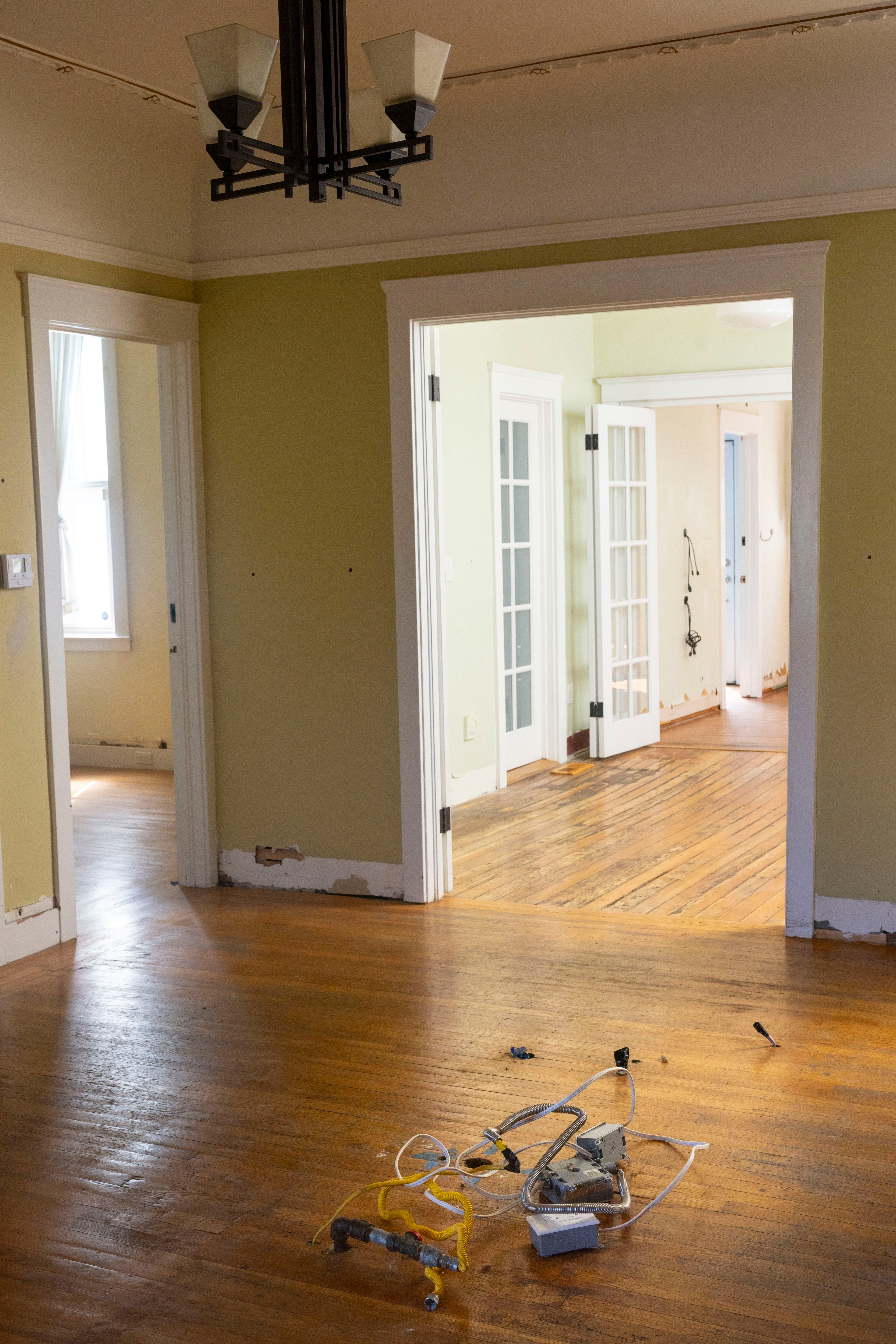 Peeled paint and flood-damaged floorboards in a sunlight home.