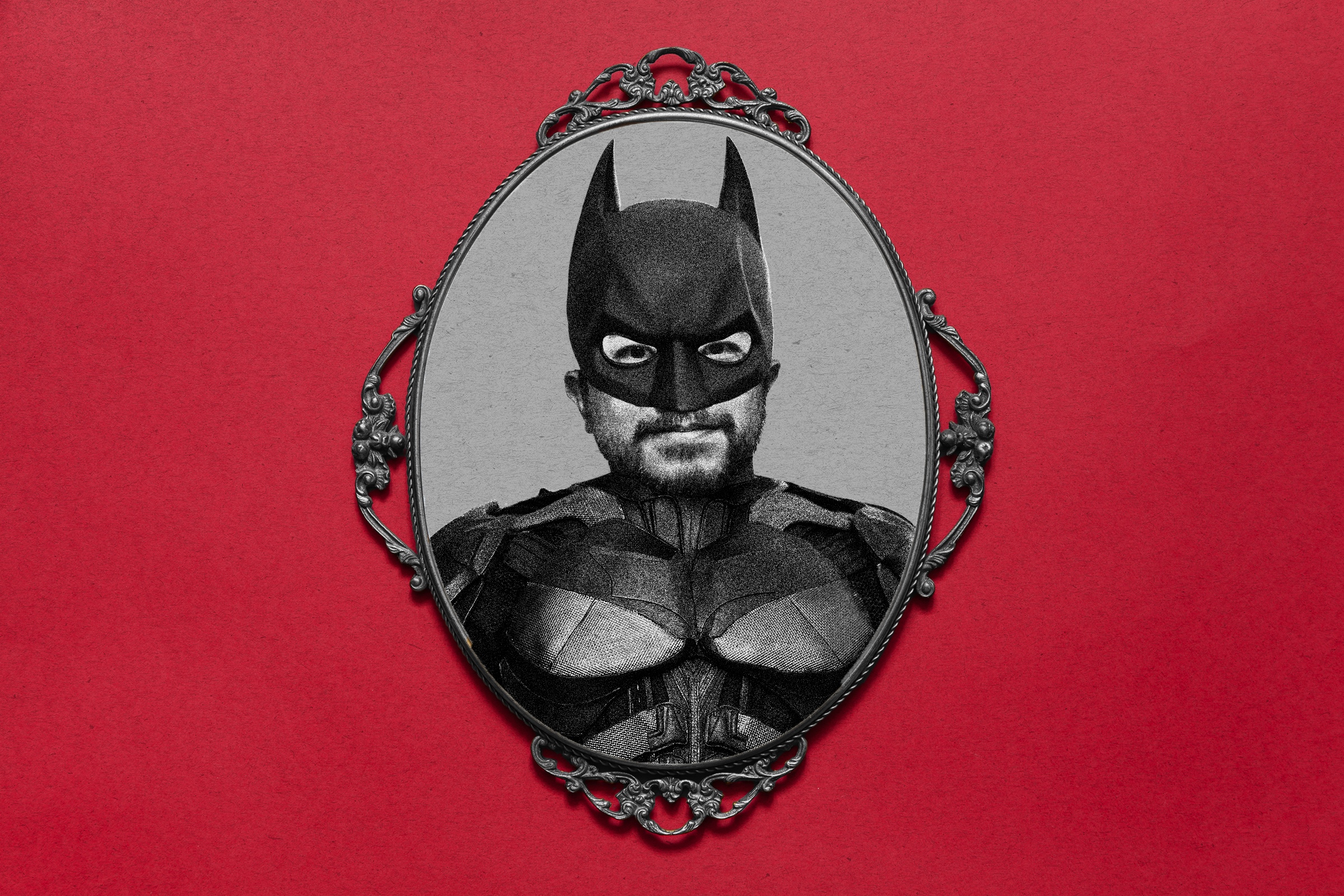 A black-and-white photo shows a person in a Batman costume inside an ornate oval frame, set against a red background.