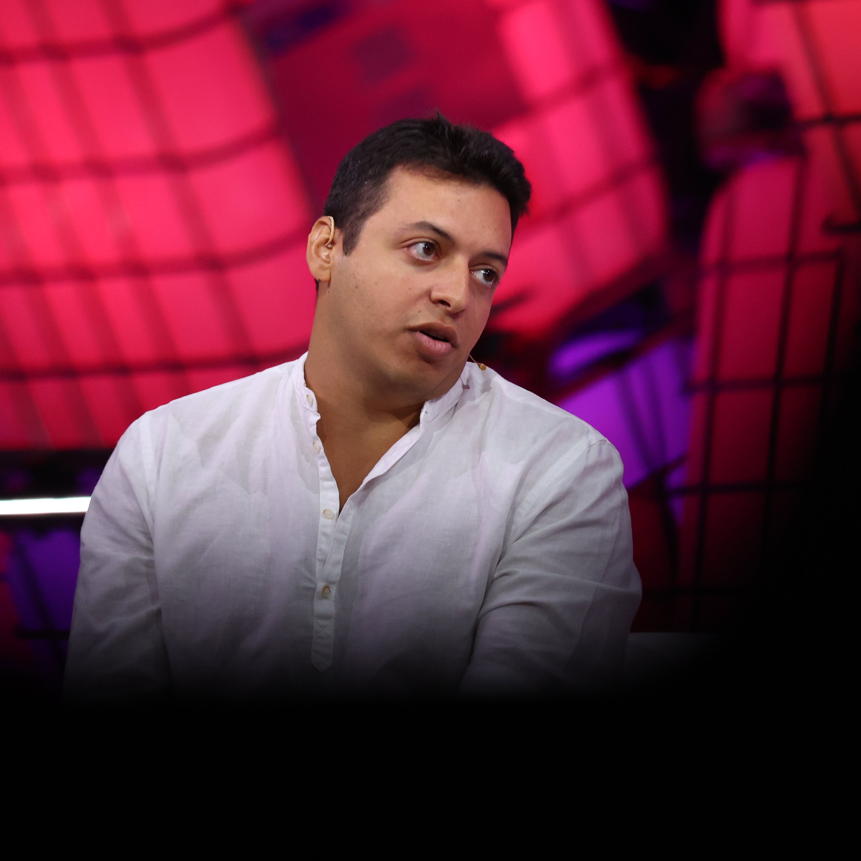 A person in a white shirt is partially visible, surrounded by a blurred, red and black grid-like background with a large dark area obscuring the bottom.