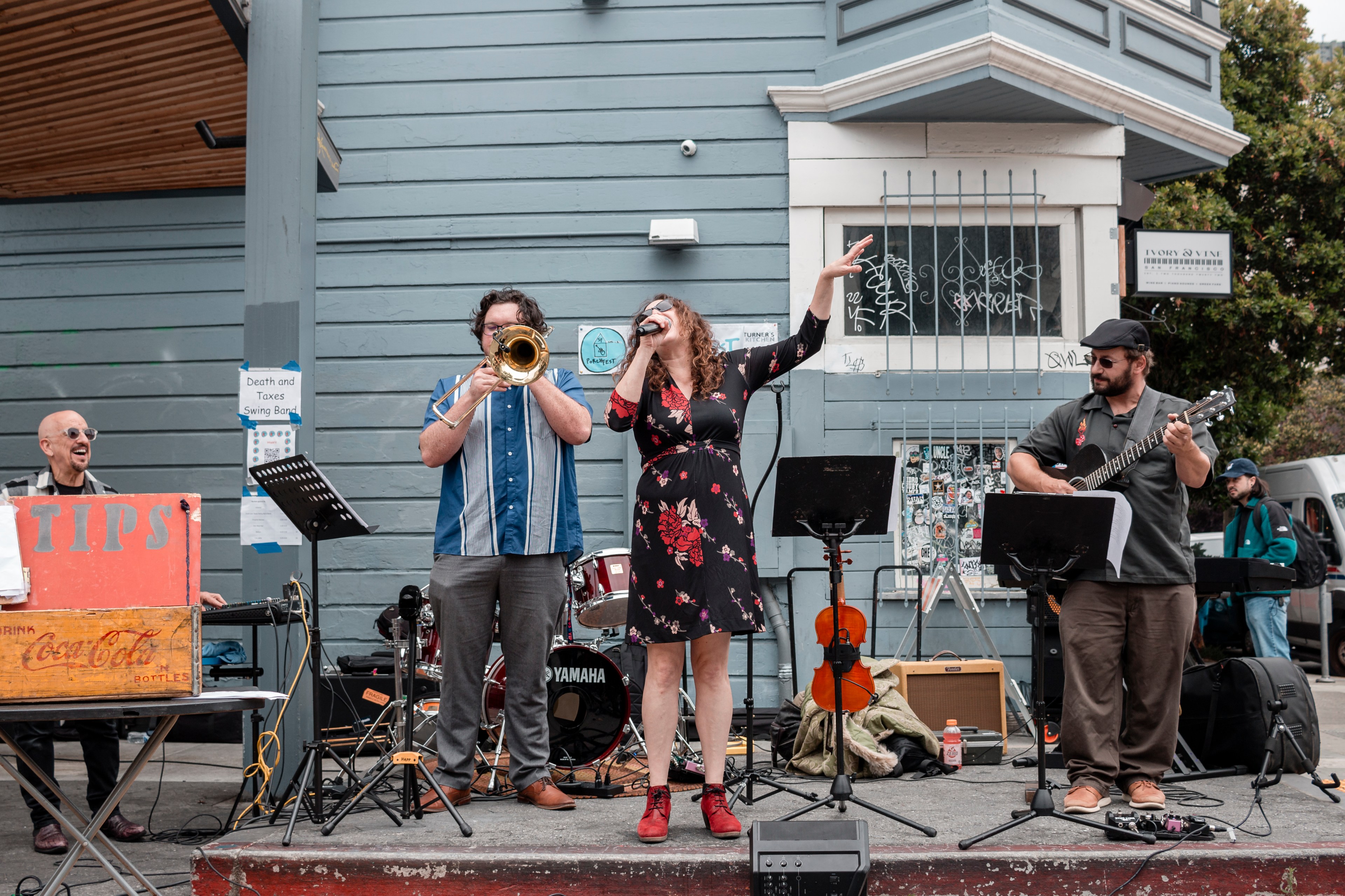 A band is performing outdoors. A keyboard player is on the left, followed by a trombonist, a singer in a floral dress, and a guitarist. A &quot;TIPS&quot; box is visible.