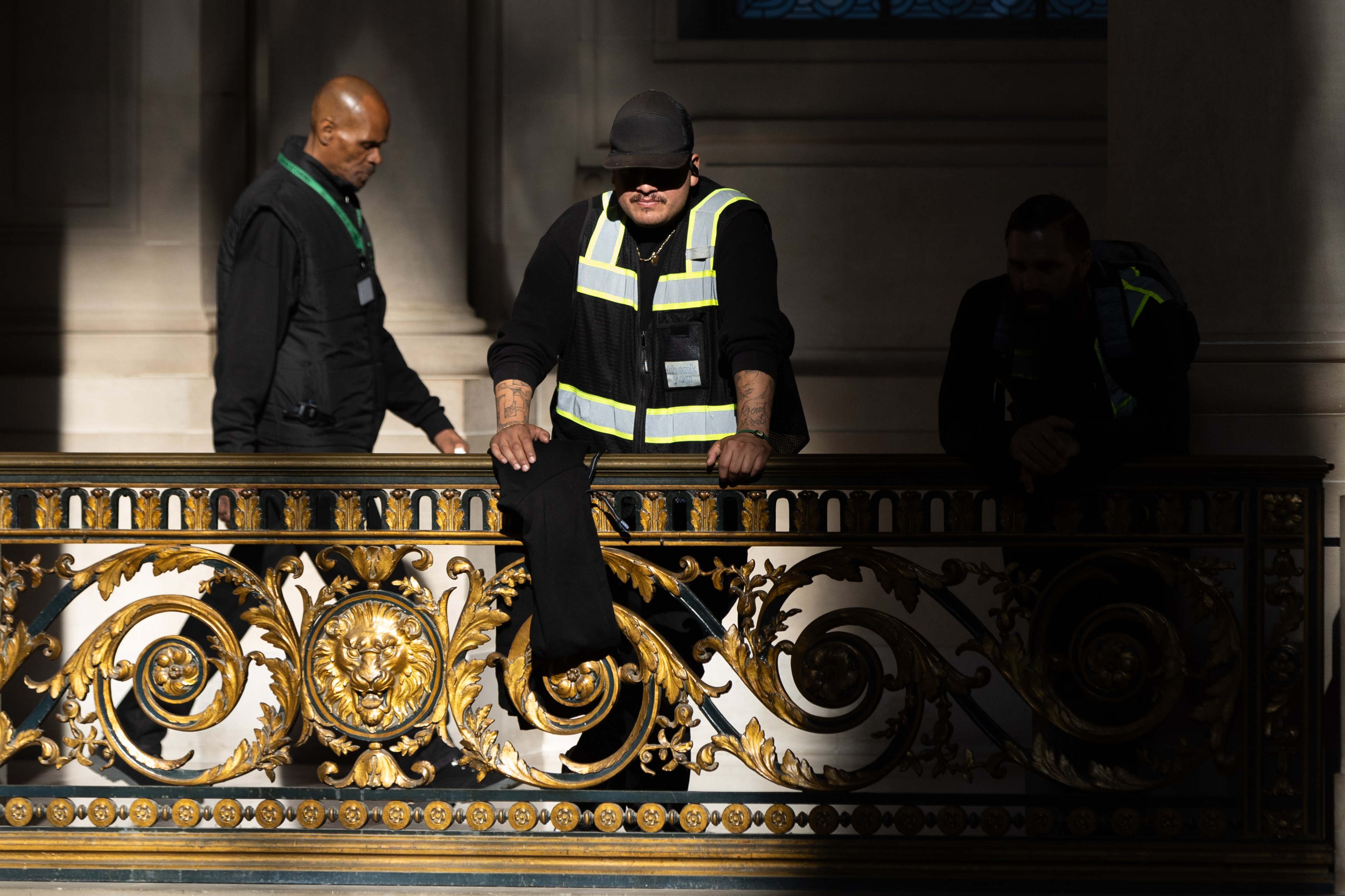 Uniformed Urban Alchemy staff stand over a railing in City Hall.