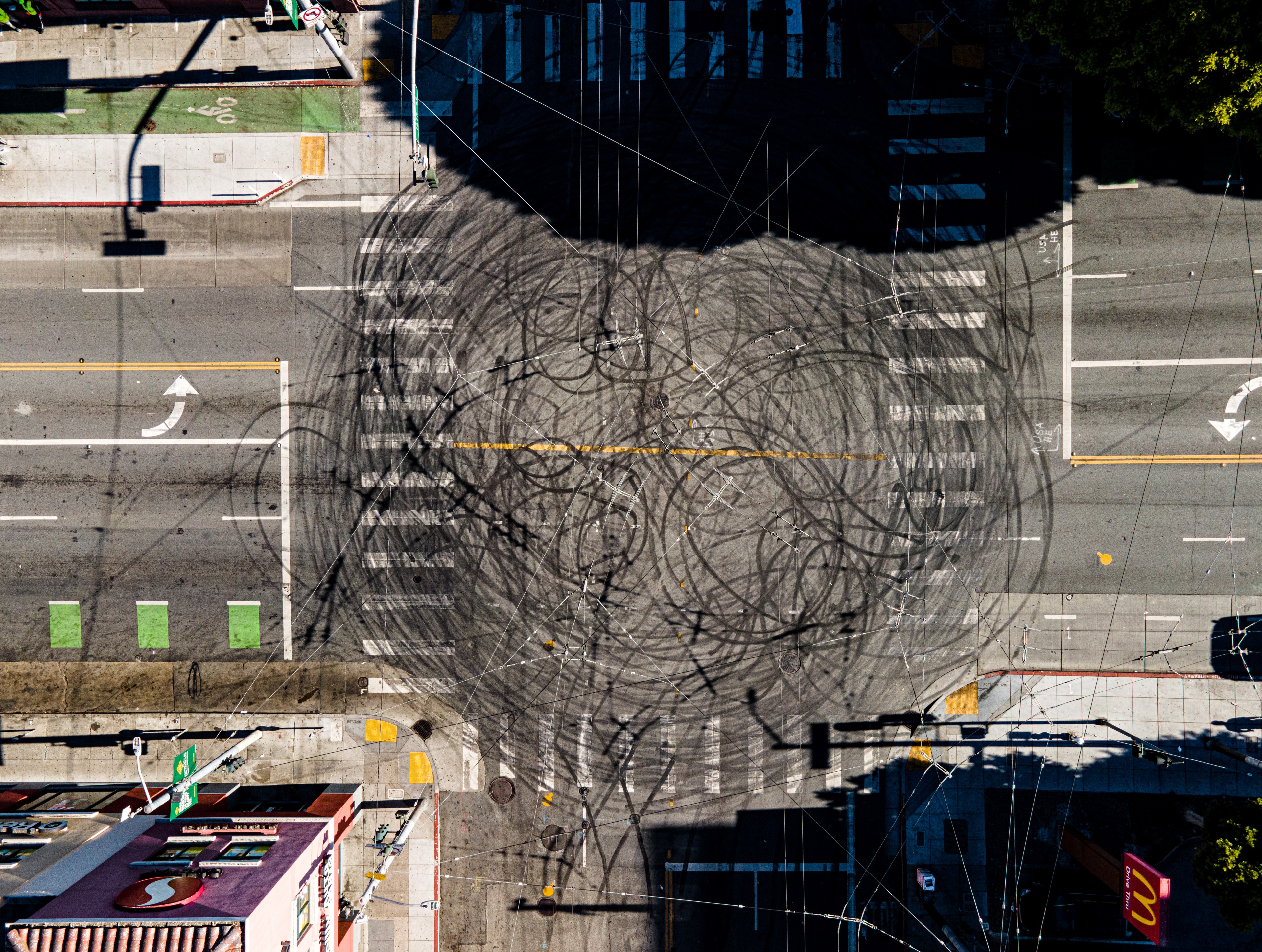 The image shows an intersection with multiple tire skid marks crisscrossing the road. Crosswalks, traffic arrows, and street markings are visible.