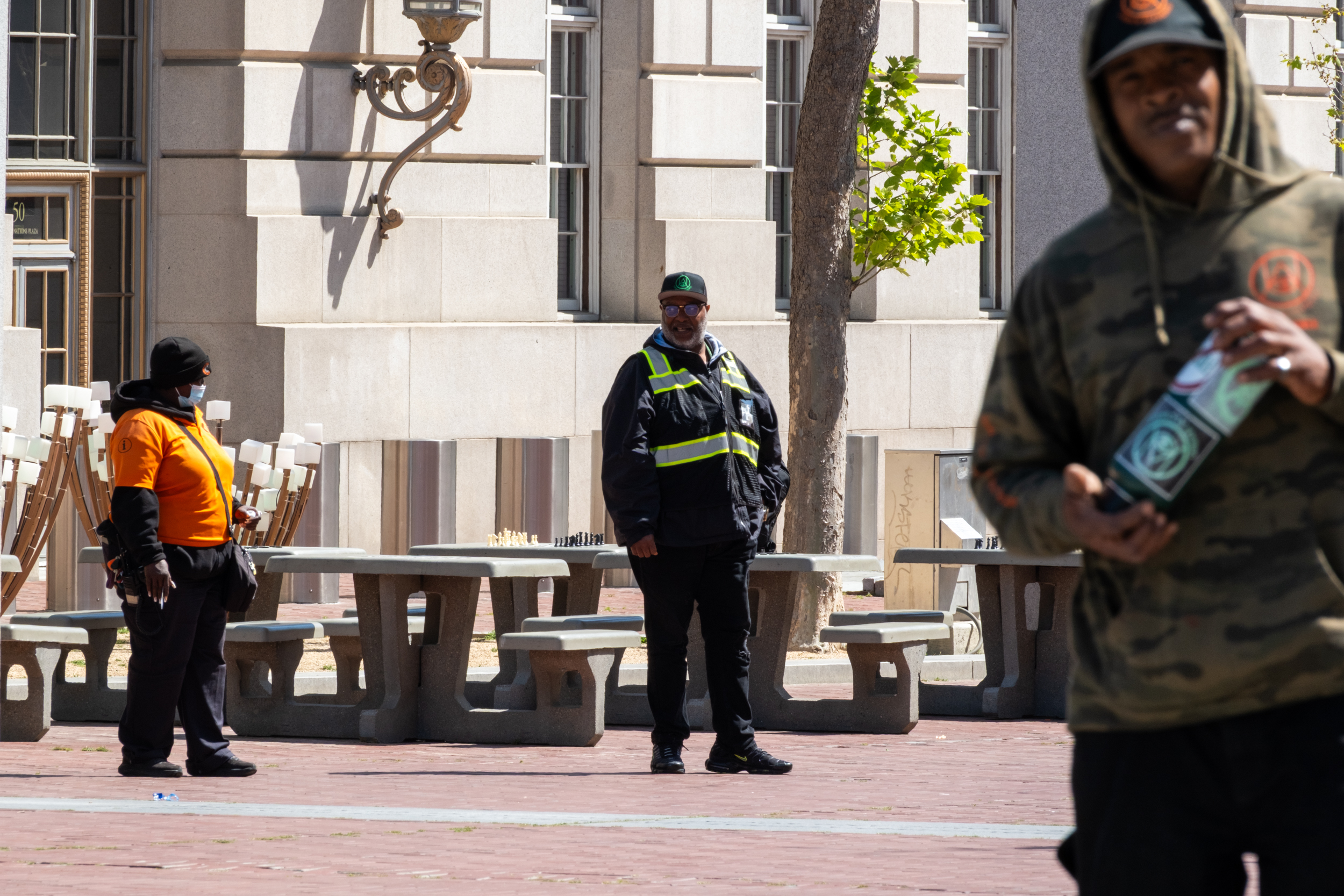 A uniformed Urban Alchemy practitioner stands on a public street with a building behind him.