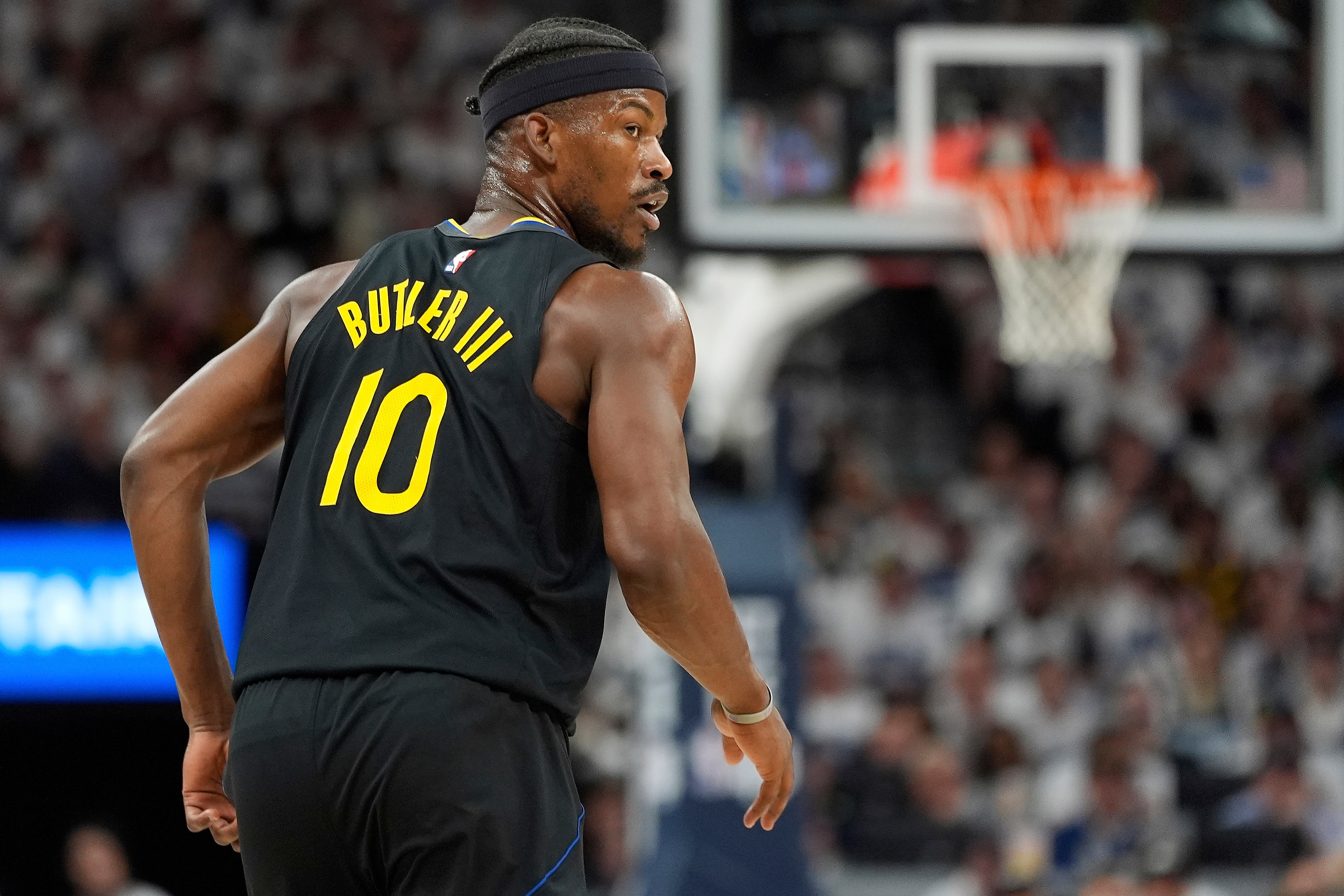 A basketball player wearing a black jersey with "Butler III" and the number 10 on the back is on the court, with a hoop visible in the background.