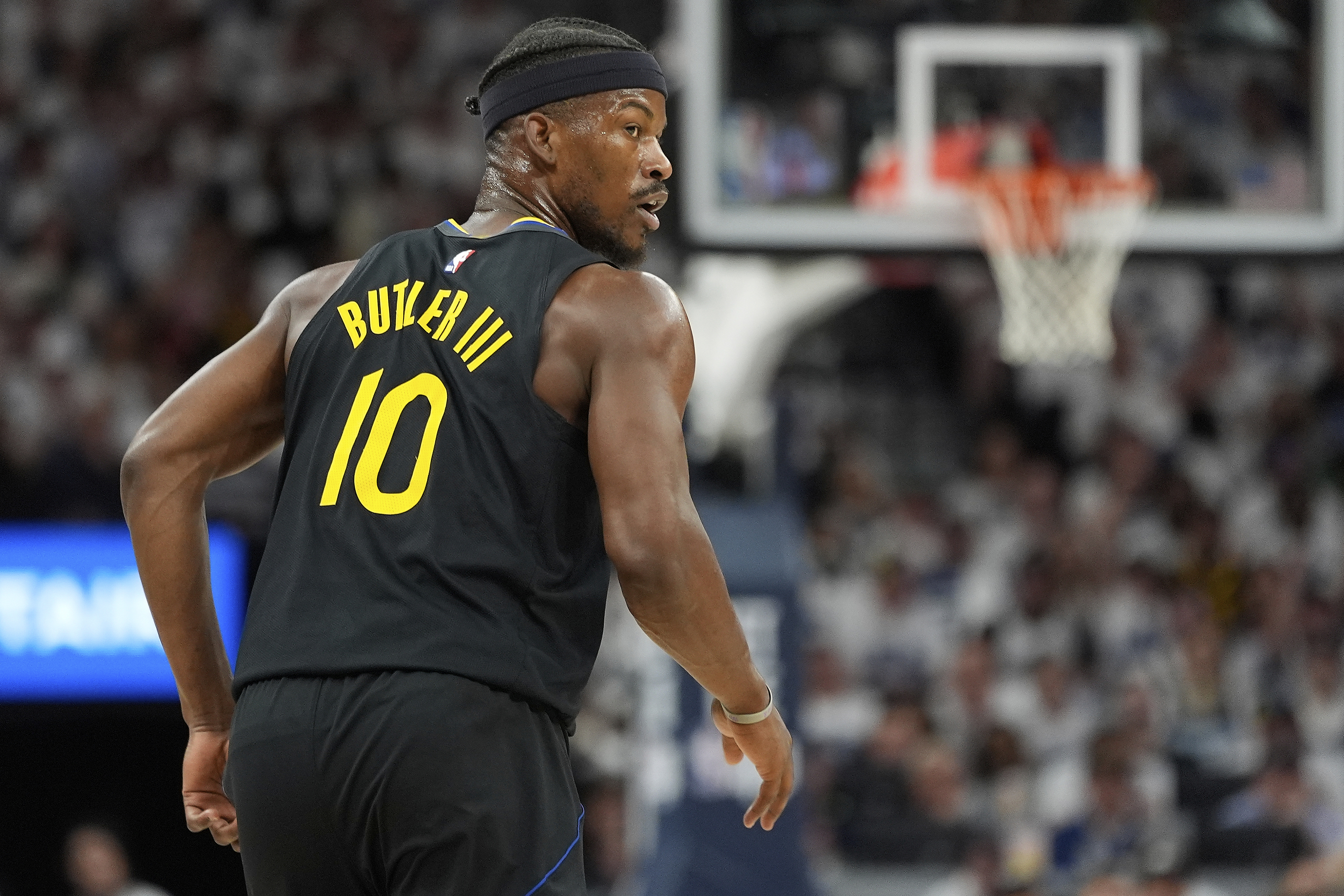 A basketball player wearing a black jersey with "Butler III" and the number 10 on the back is on the court, with a hoop visible in the background.