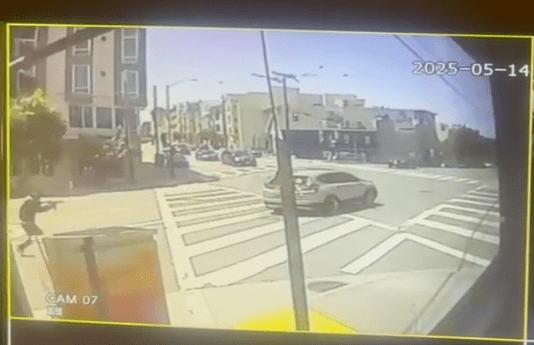 A city intersection with crosswalks is shown on a sunny day. Cars are visible on the street, and a pedestrian stands on the sidewalk. The date reads 2025-05-14.