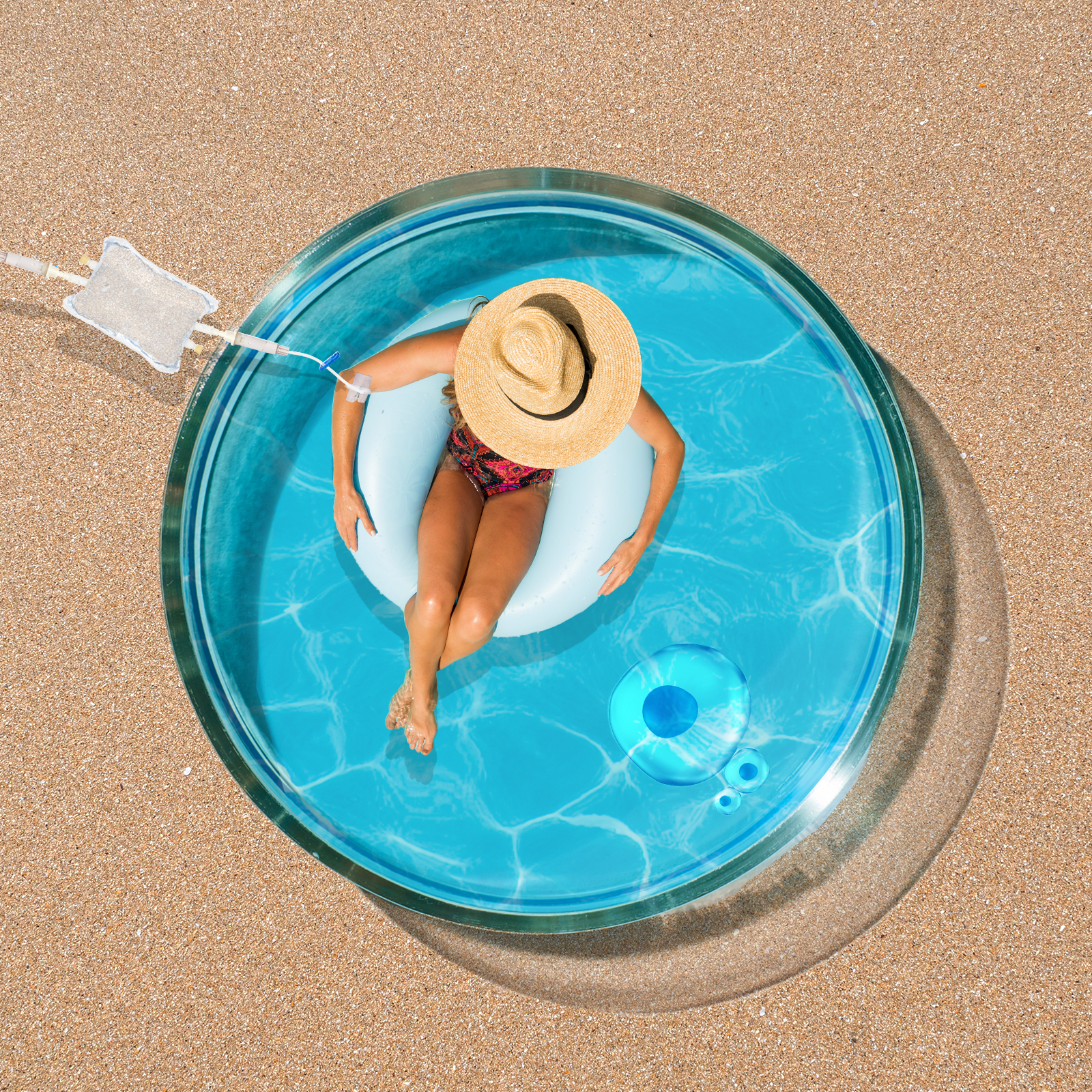 A person in a straw hat relaxes on a white float in a small, clear pool on sandy ground. Bright, sunny setting with blue water and shadows visible.