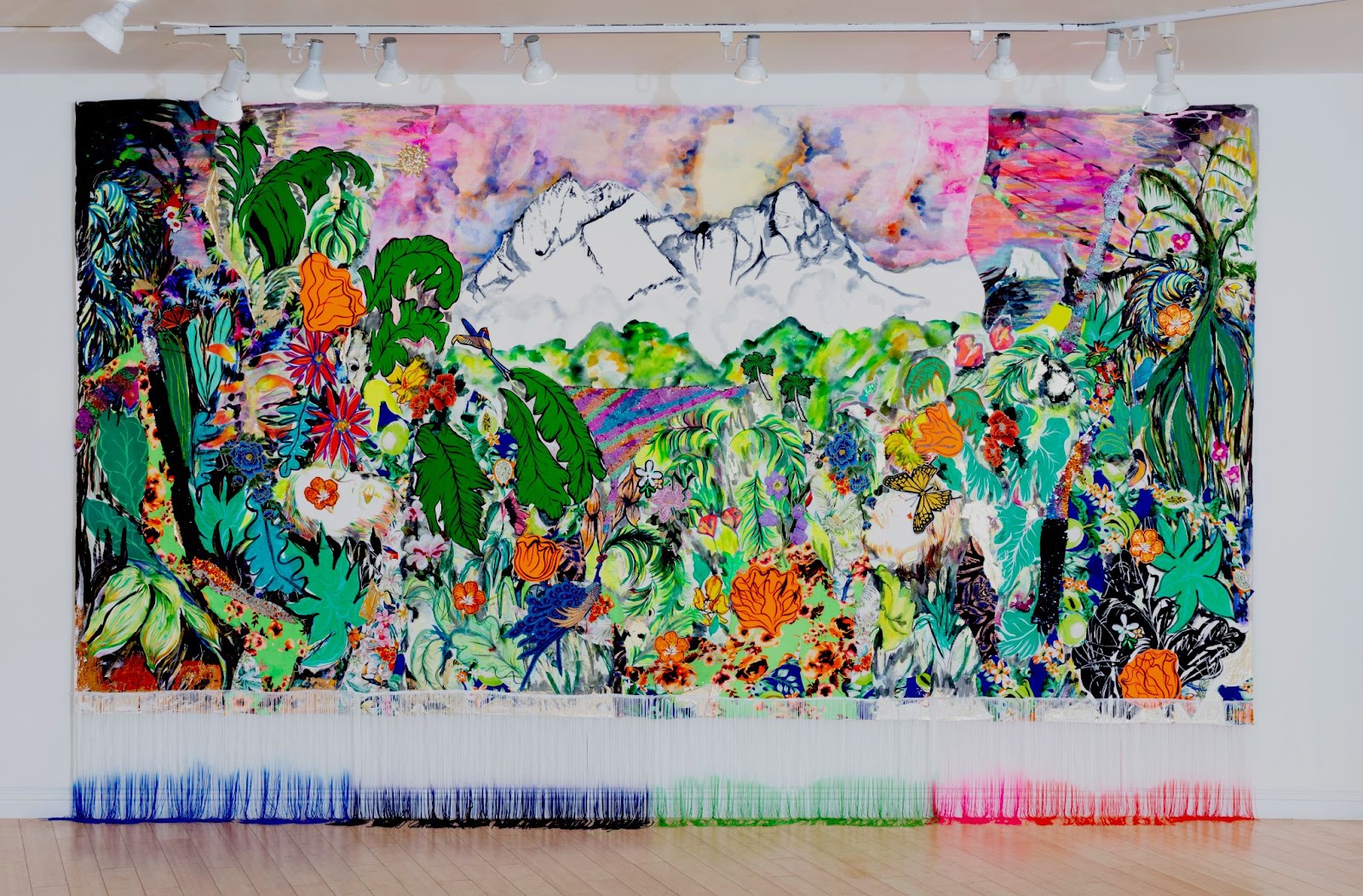 The image features a vibrant, colorful tapestry depicting a lush, tropical scene with diverse plants and flowers, set against a backdrop of snow-capped mountains.